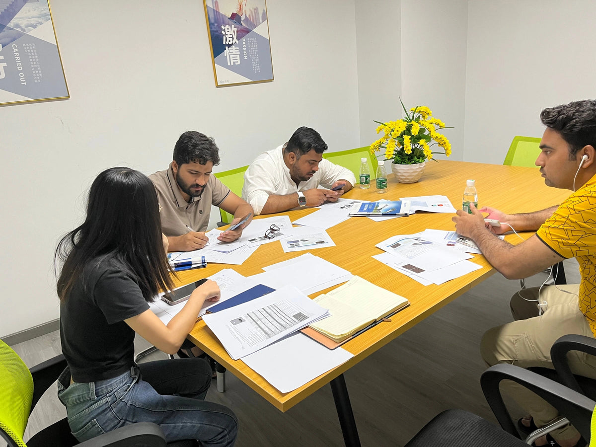 Anern team and visiting partners discussing product documents at a meeting table
